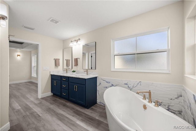 bathroom with hardwood / wood-style floors, a bathtub, vanity, and a healthy amount of sunlight