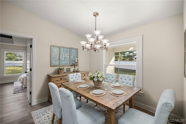 dining area with dark wood-type flooring, lofted ceiling, and an inviting chandelier