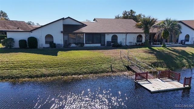 back of property with a yard, a water view, and central air condition unit