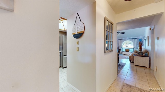 hall featuring light tile patterned floors and a textured ceiling