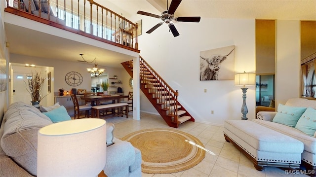 living room with a towering ceiling, ceiling fan with notable chandelier, and light tile patterned floors