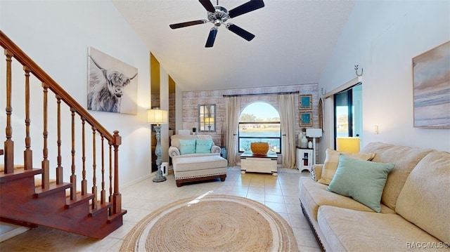tiled living area with baseboards, ceiling fan, stairs, and lofted ceiling