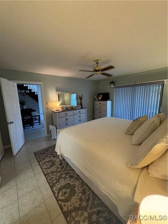 bedroom featuring a ceiling fan, light tile patterned flooring, and a textured ceiling