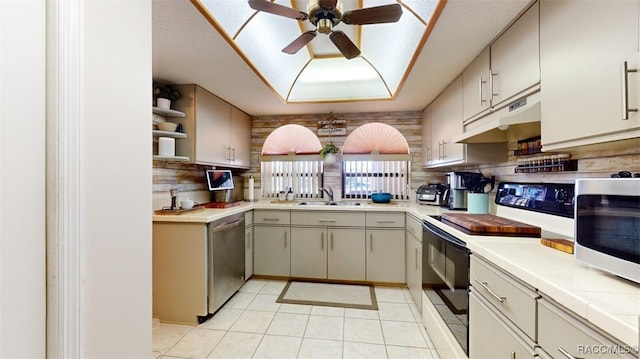 kitchen featuring tile countertops, backsplash, sink, ceiling fan, and appliances with stainless steel finishes