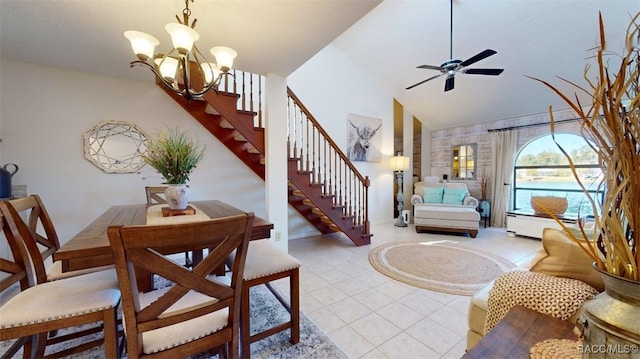 tiled dining space featuring ceiling fan with notable chandelier and high vaulted ceiling