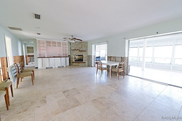 dining area featuring a fireplace, a textured ceiling, built in features, and ceiling fan