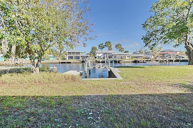 view of dock with a yard and a water view