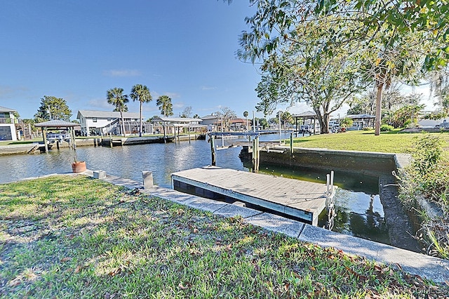 view of dock with a yard and a water view