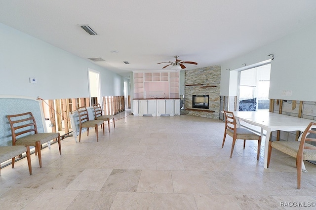 dining area featuring a stone fireplace and ceiling fan