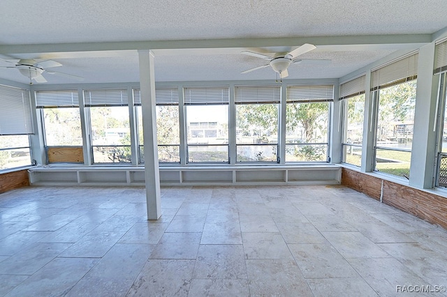 unfurnished sunroom featuring ceiling fan and plenty of natural light