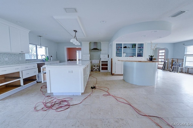 kitchen with a kitchen island, plenty of natural light, and wall chimney range hood