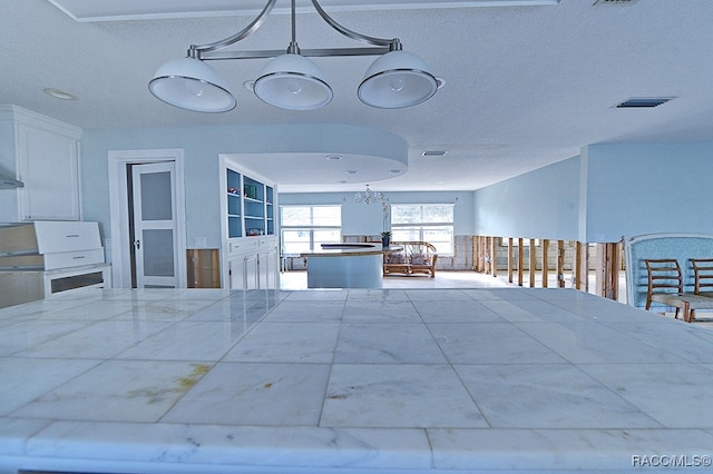 kitchen with white cabinets, a textured ceiling, and decorative light fixtures