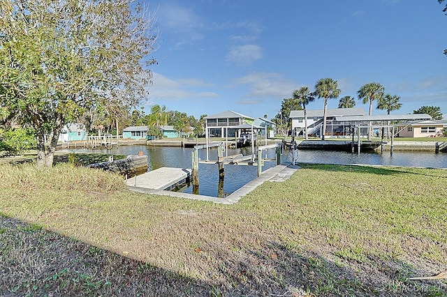 view of dock with a lawn and a water view