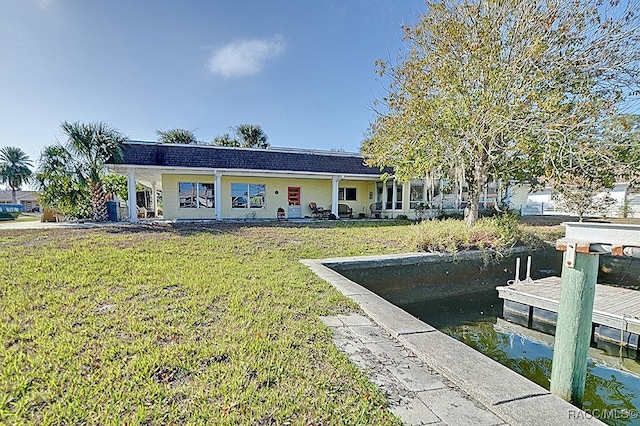 rear view of property featuring a water view and a lawn