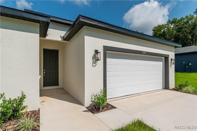 9262 N Alpinia Dr, Citrus Springs, FL 34434 - view of exterior entry featuring stucco siding, a garage, and concrete driveway