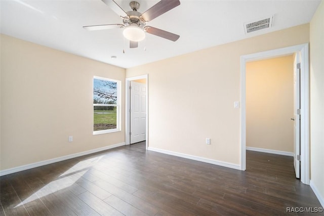 unfurnished room featuring dark wood-type flooring, a ceiling fan, visible vents, and baseboards