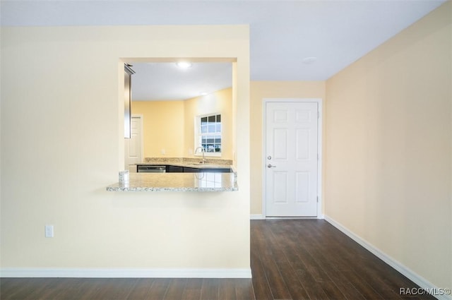 kitchen featuring baseboards, dishwasher, dark wood-style floors, light stone counters, and a sink