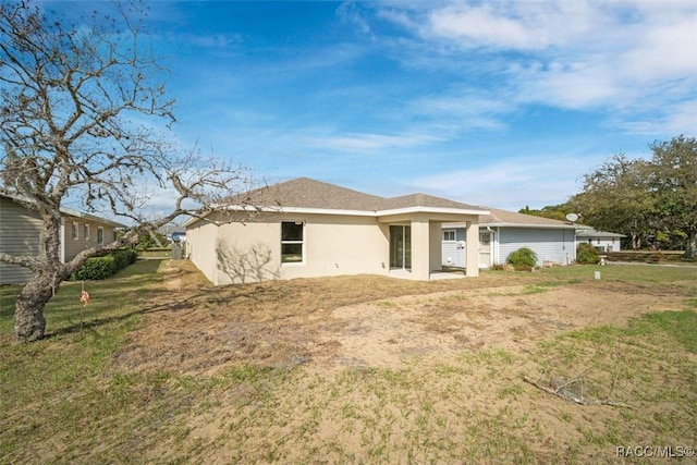 rear view of house with a lawn and stucco siding