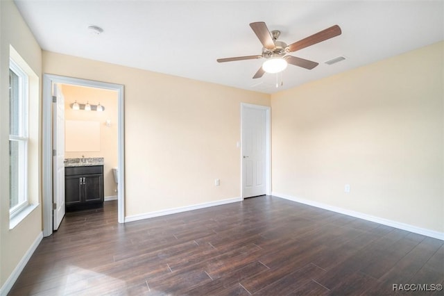 spare room with dark wood-style floors, visible vents, and baseboards