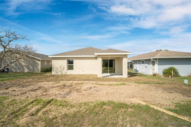 rear view of house with a yard and stucco siding