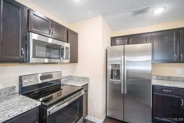 kitchen featuring stainless steel appliances, visible vents, and light stone counters