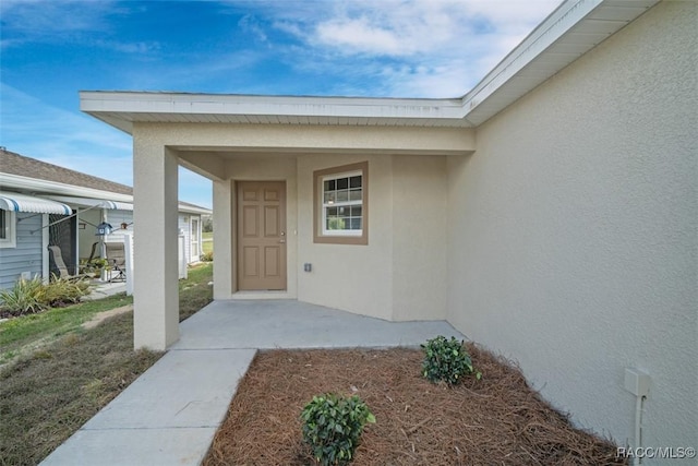 doorway to property featuring a patio and stucco siding