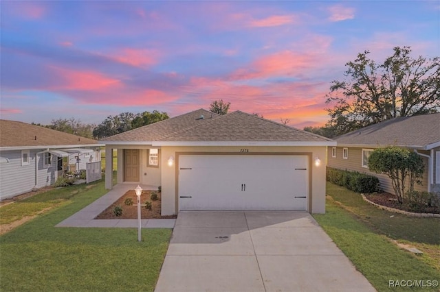 ranch-style home with roof with shingles, stucco siding, concrete driveway, an attached garage, and a front lawn