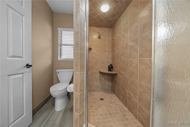 full bathroom with baseboards, toilet, and a tile shower