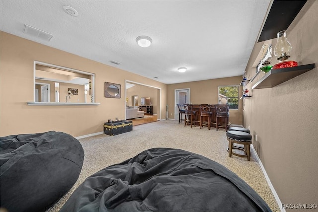 carpeted living room with visible vents, baseboards, a textured ceiling, and a dry bar