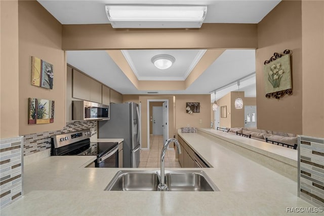 kitchen featuring a sink, a raised ceiling, light countertops, and stainless steel appliances