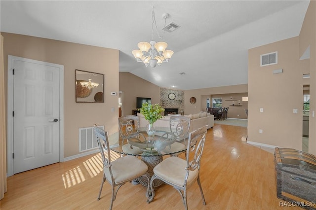 dining room with an inviting chandelier, visible vents, light wood finished floors, and vaulted ceiling