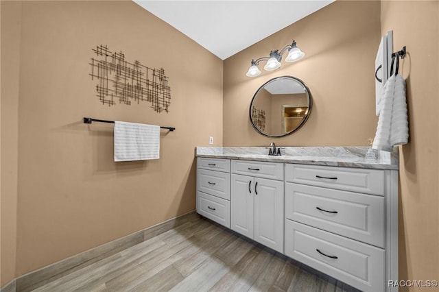 bathroom featuring baseboards, wood finished floors, and vanity