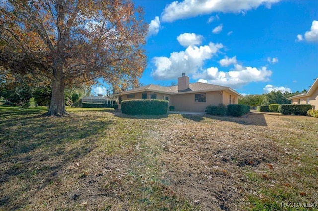 exterior space featuring a lawn, a chimney, and stucco siding