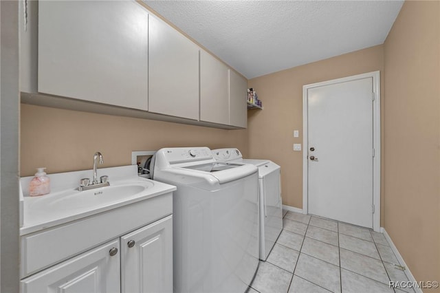 laundry area with light tile patterned flooring, cabinet space, a sink, a textured ceiling, and washer and clothes dryer