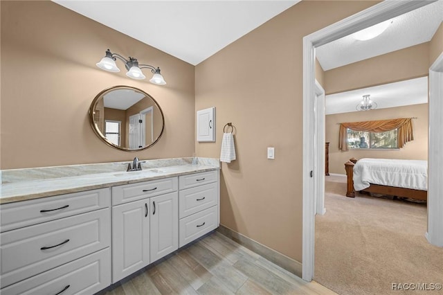 ensuite bathroom featuring ensuite bath, vanity, and baseboards