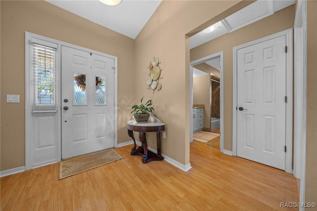 entrance foyer with vaulted ceiling, baseboards, and light wood-type flooring