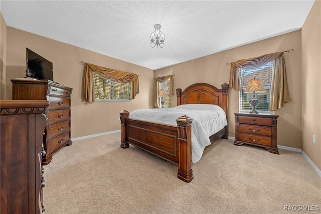 bedroom featuring light colored carpet, baseboards, and a textured ceiling