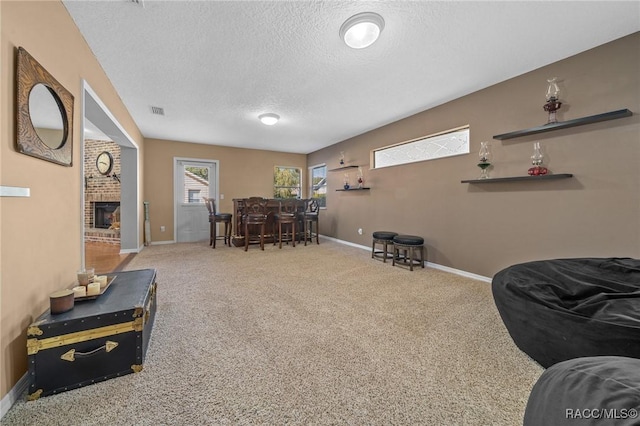 carpeted living room featuring visible vents, a brick fireplace, baseboards, a dry bar, and a textured ceiling