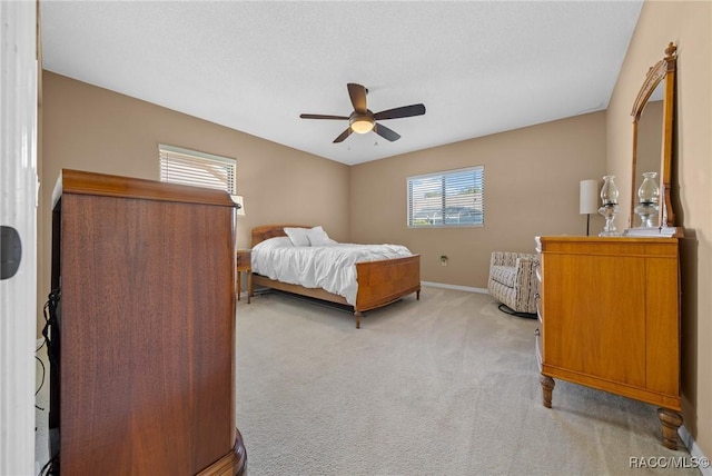 bedroom with light colored carpet, a ceiling fan, and baseboards