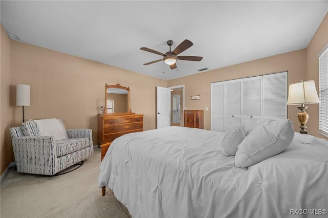 bedroom featuring baseboards, visible vents, ceiling fan, a closet, and light colored carpet