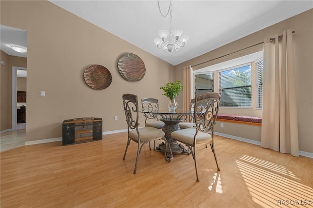 dining room featuring baseboards, light wood-style floors, an inviting chandelier, and vaulted ceiling