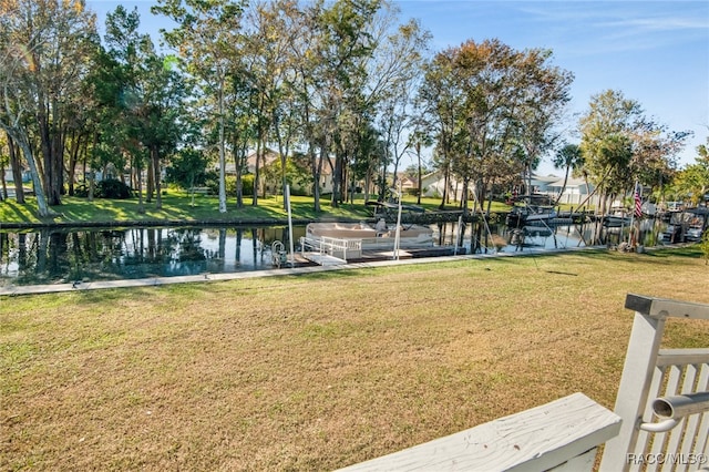 view of property's community featuring a lawn, a water view, and a boat dock