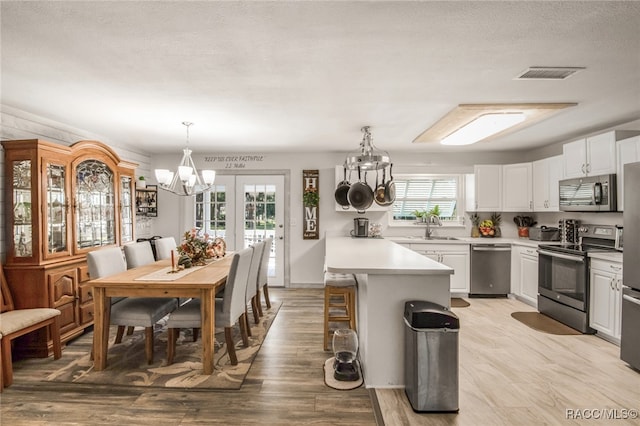 kitchen with sink, a notable chandelier, pendant lighting, white cabinets, and appliances with stainless steel finishes