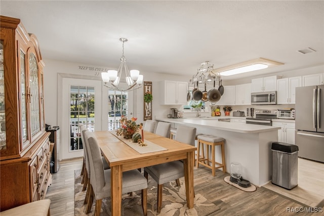 dining space with sink, an inviting chandelier, and light wood-type flooring