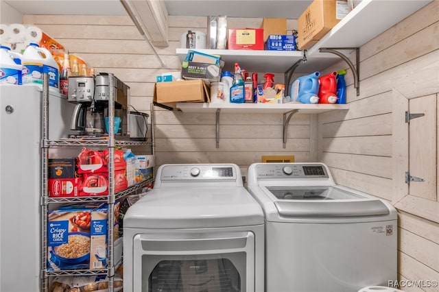 washroom featuring washer and clothes dryer and wood walls