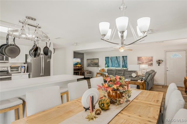 dining room with ceiling fan with notable chandelier and light wood-type flooring