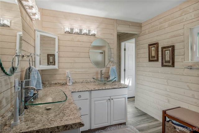 bathroom with wood walls, vanity, and wood-type flooring