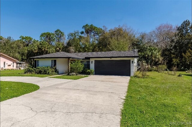 ranch-style home with a front yard, an attached garage, stucco siding, and concrete driveway