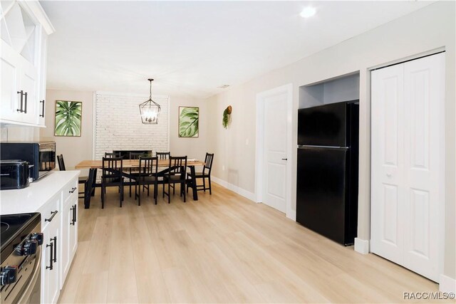 kitchen with white cabinets, freestanding refrigerator, stainless steel range with electric cooktop, and light wood finished floors