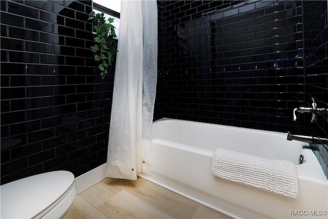 bathroom featuring toilet, shower / bathtub combination with curtain, and wood finished floors